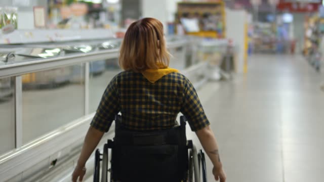 Frau-im-Rollstuhl,-die-Lebensmittel-im-Supermarkt-einkaufen-zu-tun