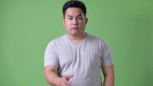 Joven-guapo-sobrepeso-hombre-asiático-sobre-fondo-verde