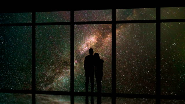 The-man-and-woman-standing-near-windows-on-a-meteor-shower-background