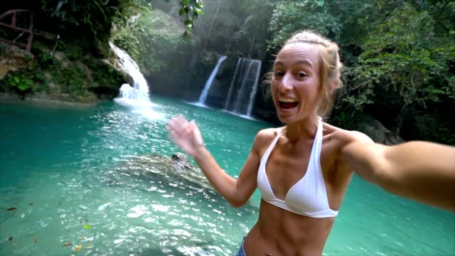 Junge-Frau-unter-Selfie-Porträt-mit-einem-wunderschönen-Wasserfall-auf-der-Insel-Cebu-in-den-Philippinen.-Die-Leute-reisen-Natur-Selfie-Konzept.-Eine-Person,-die-nur-genießen,-Natur-und-Ruhe-in-einer-friedlichen-Umgebung-Slow-Motion-video