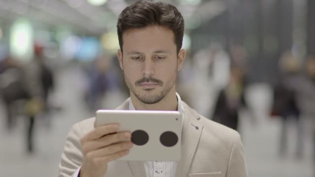 Hübscher-junger-Geschäftsmann,-Verfassen-von-Texten-auf-digitale-Tablet-im-öffentlichen-Raum