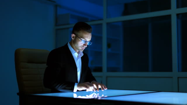 The-businessman-working-with-a-sensor-display-in-the-dark-room