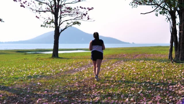 Una-mujer-asiática-gorda-corriendo-en-la-luz-del-sol-natural-por-la-noche.
Ella-está-tratando-de-perder-peso-con-el-ejercicio.--concepto-de-salud-con-ejercicio.-Cámara-lenta