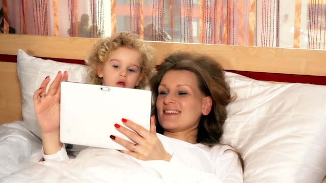 niña-caucásica-y-madre-mujer-con-Tablet-PC-en-la-cama