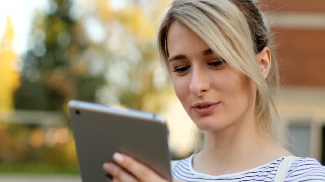 Close-up-portrait-of-young-female-student-using-tablet-computer-outside.-Girl-doing-online-shopping-on-tablet-pc