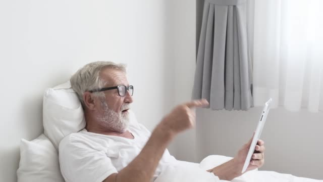 Abuelo-o-anciano-usando-tecnología-de-tableta-y-Anímese-en-la-cama