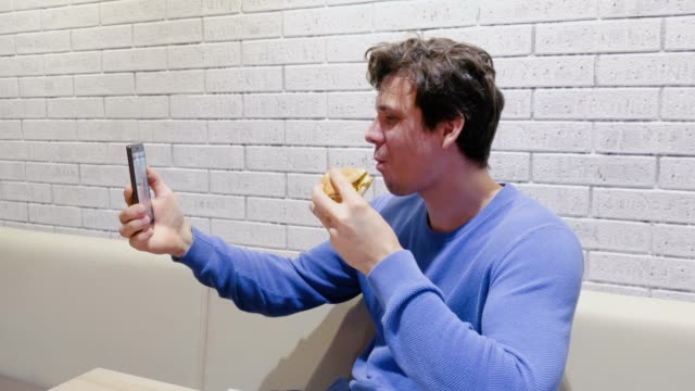 El-hombre-está-comiendo-una-hamburguesa-con-gusto-y-deleite-en-la-cafetería.