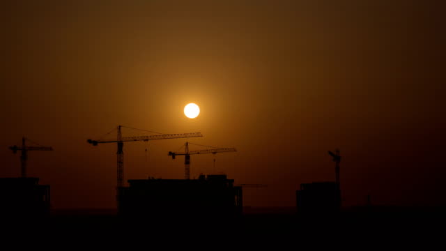 The-building-with-cranes-on-a-sunset-background.-time-lapse