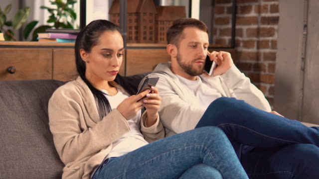 Couple-sitting-on-the-couch-while-communicating-with-friends