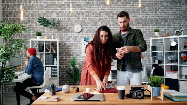 Girl-putting-things-on-table-while-guy-shooting-flat-lay-with-smartphone