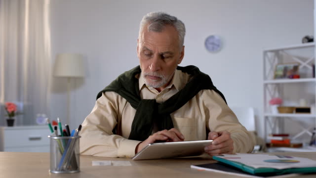 Senior-hombre-usando-la-tableta-para-pagar-préstamos-e-impuestos-en-línea,-la-transacción-bancaria
