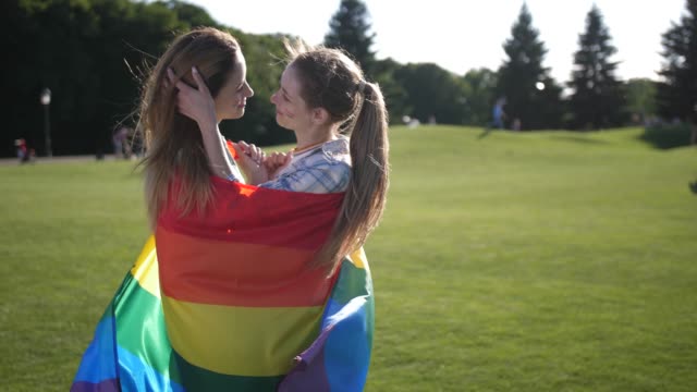 Young-gay-couple-standing-wrapped-in-lgbt-flag