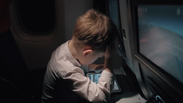 Niño-jugando-pad-juego-de-ajedrez-cuando-se-viaja-en-avión-por-la-noche