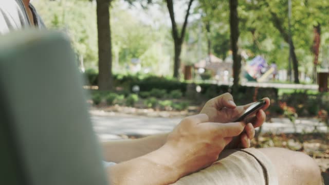 Man-Chatting-On-Mobile-Phone.-Relaxed-Guy-Sit-And-Looking-At-Mobile-Phone-In-City-Park.-Beautiful-Male-Having-Chat-Using-Smartphone-Outdoors.-Man-Chatting-With-Friend.