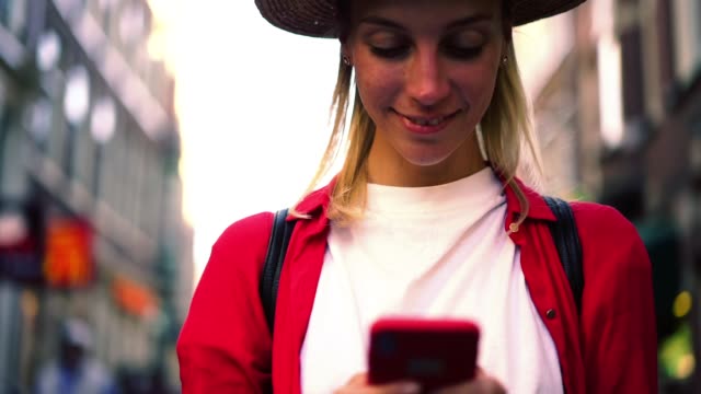 Fröhliche-Hipster-Mädchen-stehen-auf-der-Straße-senden-TEXTnachrichten-über-Handy-Gerät