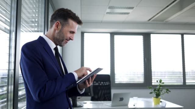 Happy-businessman-working-in-office-with-tablet