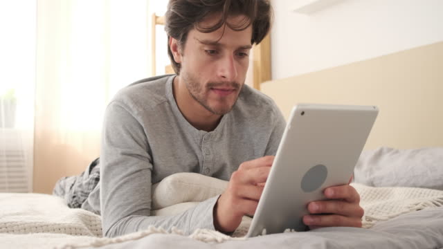 Hombre-usando-tableta-digital-en-la-cama-en-casa