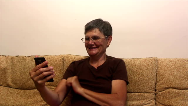 Attraktive-erwachsene-Frau-lesen-einen-News-Feed-auf-einem-Smartphone,-während-auf-einem-Sofa-zu-Hause-sitzen.