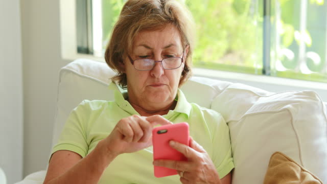 Senior-older-woman-holding-smartphone-device-pressing-screen-with-finger