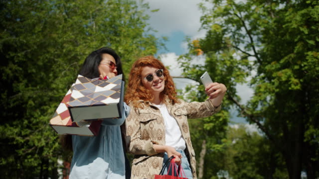 Porträt-glücklicher-Studentinnen,-die-im-Park-Selfies-mit-Einkaufstaschen-machen