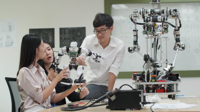Ingeniero-adolescente-asiático-ensamblando-y-probando-respuestas-robóticas-en-laboratorio.-Los-arquitectos-diseñan-la-reunión-de-circuitos-comparten-ideas-tecnológicas-y-un-robot-de-desarrollo-colaborador.
