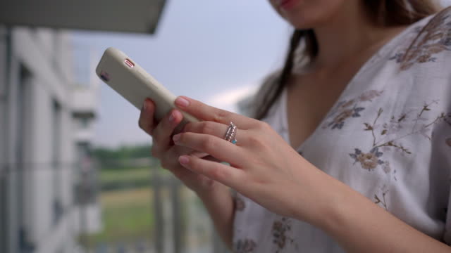 woman-is-holding-mobile-phone-and-tapping-on-screen,-closeup