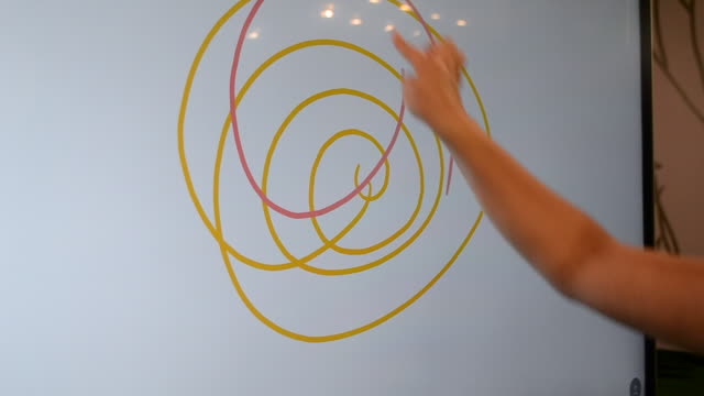 Chica-dibuja-con-su-dedo-líneas-espirales-de-diferentes-colores-en-un-toque-grande