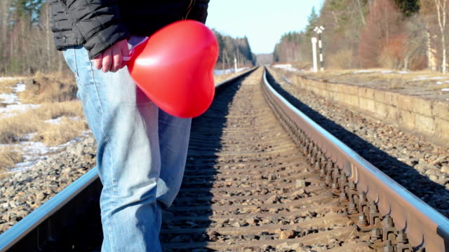 Hombre-con-globo-en-forma-de-corazón-rojo-en-el-ferrocarril