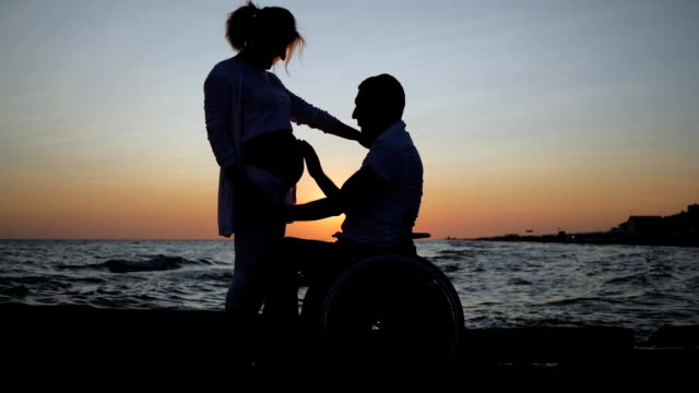 Behinderten-im-Rollstuhl-hört-Bauch-seiner-Frau-am-Abend,-verkrüppelten-Liebe,-trächtige-Weibchen-mit-ungültigen-Mann
