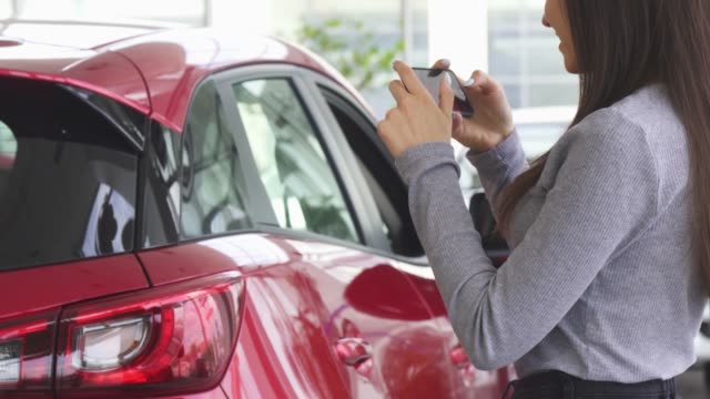 Cropped-shot-of-a-woman-taking-photos-of-her-new-car