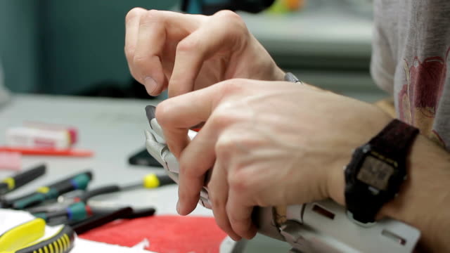 Junger-Ingenieur-arbeitet-mit-mechanische-Hand-Prothese-im-Arbeitsbereich-in-Unternehmen