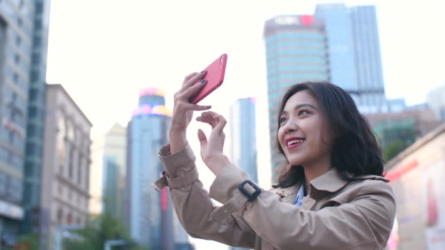 Bastante-feliz-joven-mujer-asiática-mediante-teléfono-móvil-tomar-fotografía-en-la-ciudad-China-de-Chengdu-a-tarde-en-cámara-lenta
