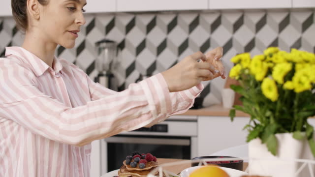Frau-fotografieren-Pfannkuchen-mit-Obst-beim-Frühstück-in-der-Küche