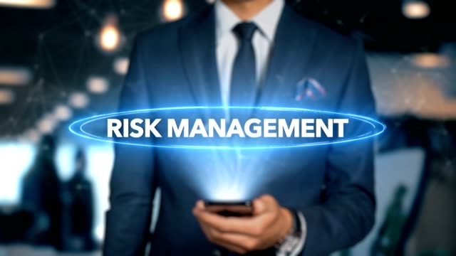 Businessman-With-Mobile-Phone-Opens-Hologram-HUD-Interface-and-Touches-Word---RISK-MANAGEMENT