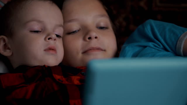 Footage-two-boys-using-tablet-pc-lying-on-sofa.