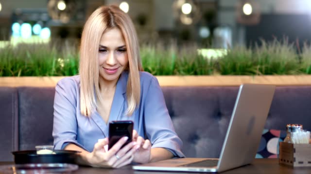 Portrait-of-happy-smiling-young-female-businesswoman-typing-message-or-chatting-using-smartphone