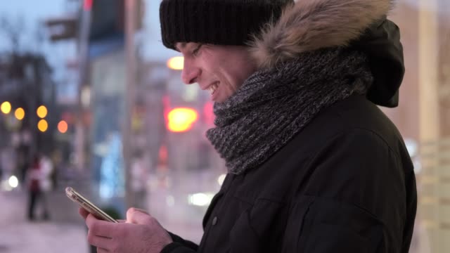 Man-text-messaging-on-mobile-phone-outdoors-in-winter