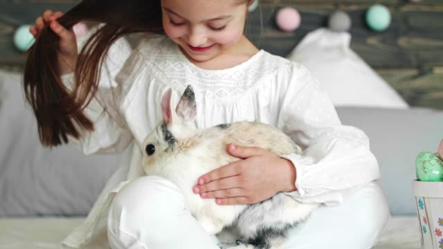 Chica-sentada-junto-a-la-cesta-de-Pascua-y-acariciando-el-conejo