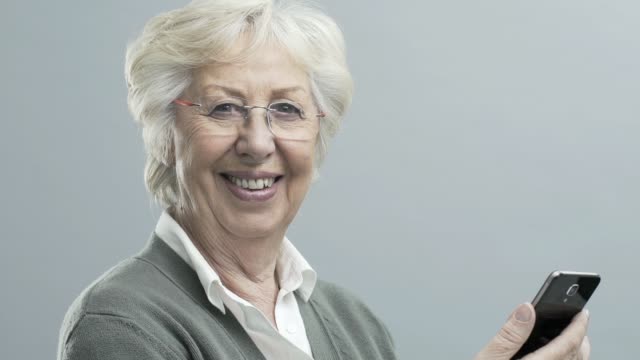 Lächelnde-ältere-Dame-mit-einem-Touchscreen-Smartphone