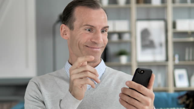 Excited-Man-Enjoying-Success-while-Using-Smartphone