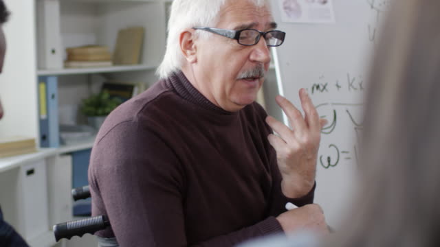 Profesor-masculino-en-gafas-hablando-con-estudiantes