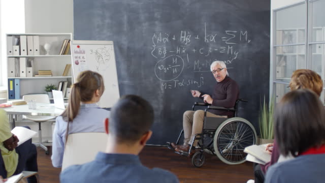 Profesor-sentado-en-silla-de-ruedas-y-hablando-con-los-estudiantes