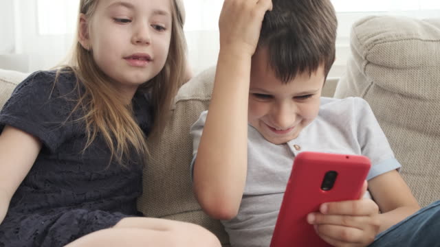 Children-using-mobile-phone-on-sofa