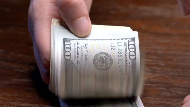 Nahaufnahme-Hand-flippt-neue-hundert-Dollar-Scheine-Geld