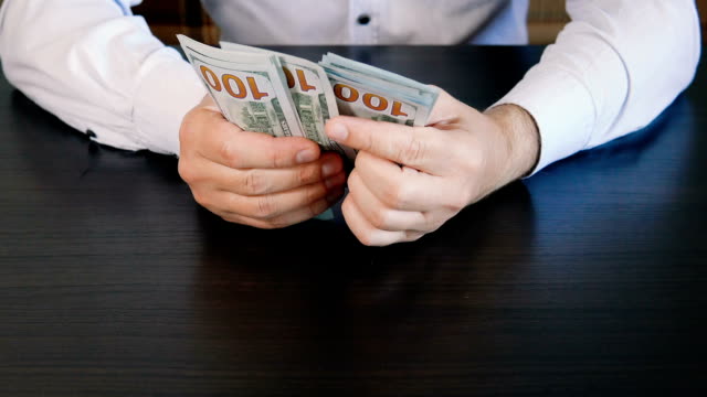 Man-hands-counting-hundred-dollar-bills