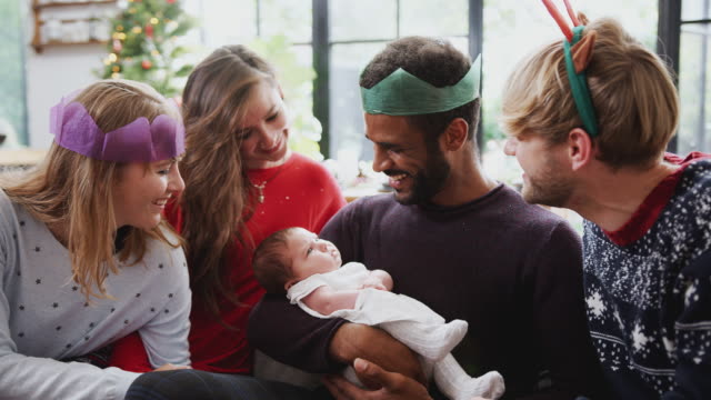 Homosexuell-männliche-paar-mit-adoptierten-Baby-Tochter-feiert-erste-Weihnachten-mit-Freunden
