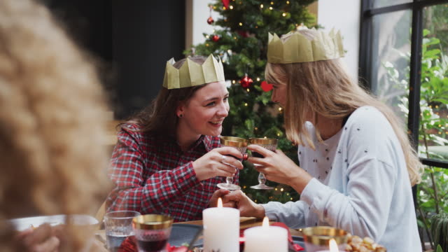 Homosexuell-weibliche-paar-sitzen-um-Tisch-für-Weihnachten-Abendessen-flüstern-und-Toast-machen