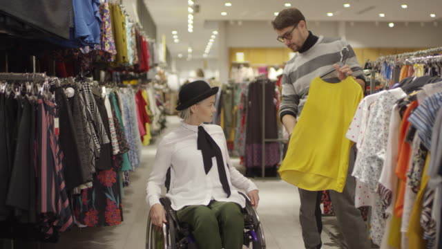 Frau-im-Rollstuhl-Einkaufen-in-Kleidung-Store-mit-Freunden