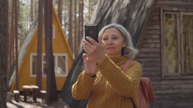 Mujer-envejecida-haciendo-fotos-en-el-campamento-turístico