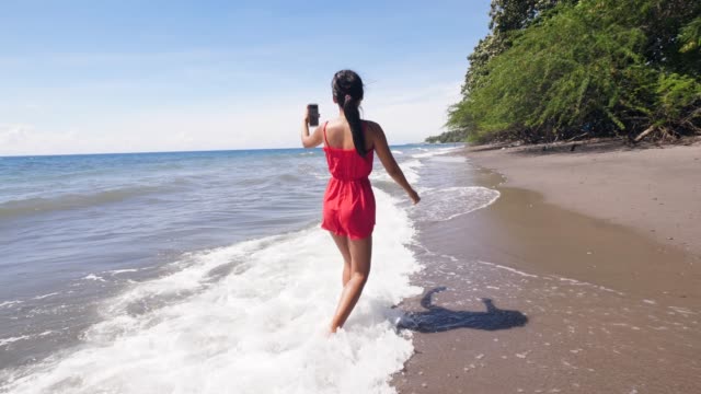 Travel-Frau-Vlogger-am-Strand-zu-Fuß-und-Aufnahme-vlog-auf-dem-Smartphone.